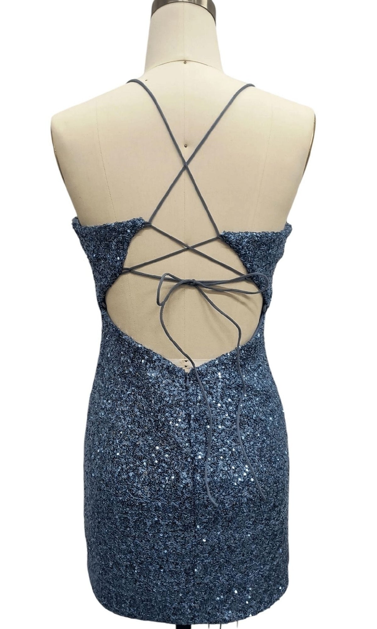 A mannequin showcases the back of the Short Blue Sequin Hoco Dress: 12661, featuring thin crisscross straps and an open back design.